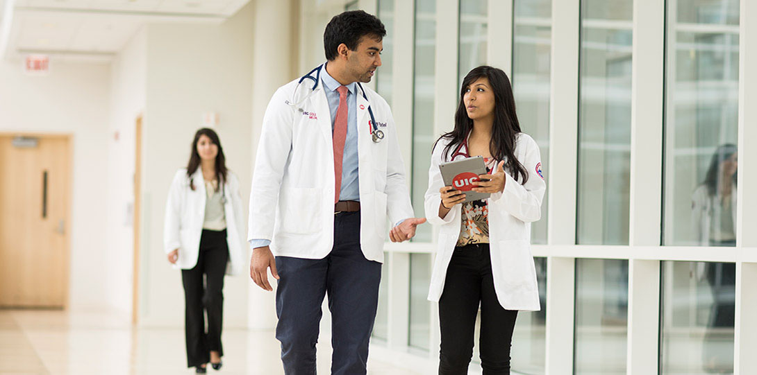 Health Sciences students in lab coats walking and talking together